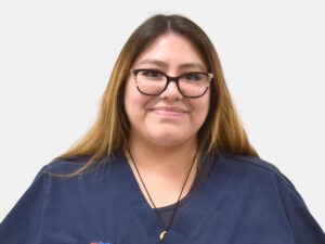 Veterinary Assistant standing in front of a wall wearing blue scrubs that say PetSmart Veterinary Services